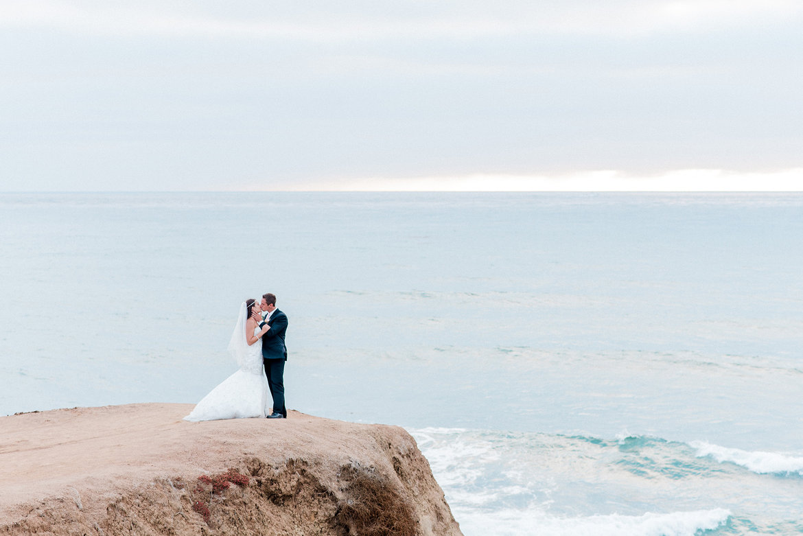 bride and groom kissing near the ocean