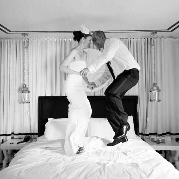 bride and groom jumping on the bed