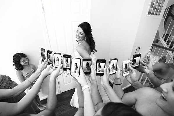 bridesmaids with iphones taking picture of the bride