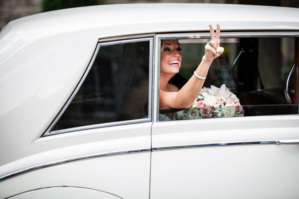 bride making peace sign out the car window