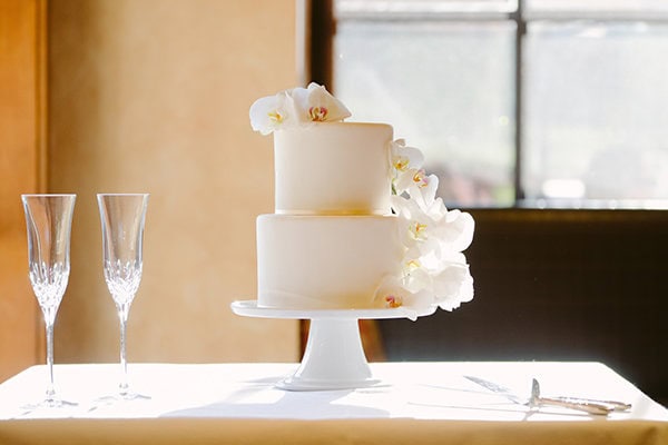 Elegant wedding cake with orchids on a white table, bridal celebration decor.