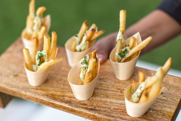 A delicious serving of French fries topped with cheese and herbs in small wooden cups.