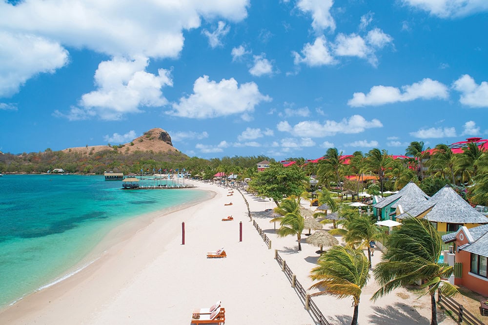 A pristine Caribbean beach with turquoise waters, white sand, and tropical palm trees.
