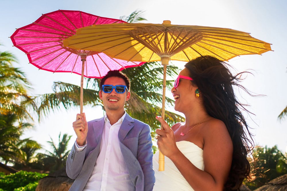 A happy couple enjoying a tropical outdoor wedding under colorful umbrellas.