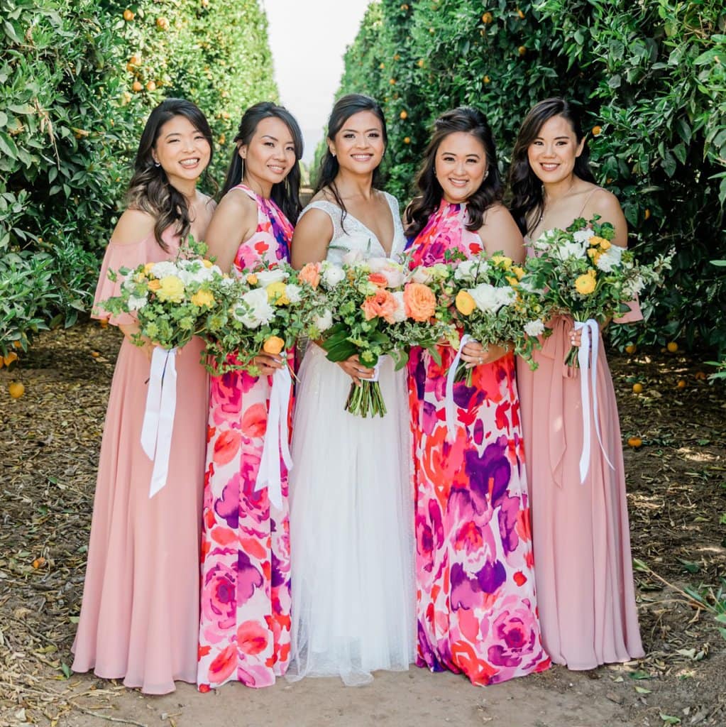 Bridesmaids and bride holding bouquets in a garden wedding setting.