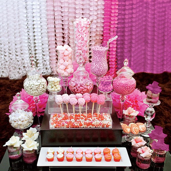 Pink candy and dessert table with sweets and treats for a bridal celebration.