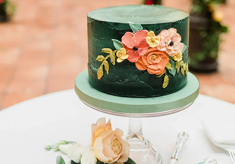 Elegant green wedding cake with pink and peach floral decorations.