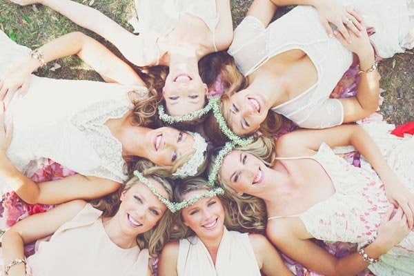Group of happy bridesmaids lying on the grass at a wedding celebration.
