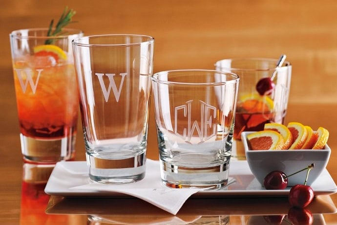 A colorful cocktail with fresh fruit garnishes and empty glasses on a white tray.