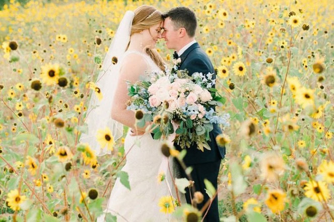 A couple sharing a romantic moment in a sunflower field on their wedding day.