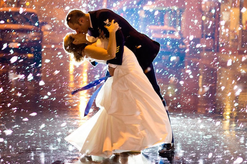A couple dancing at their wedding reception with colorful lights and confetti.