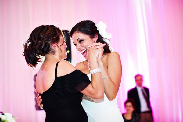 A joyful bride dancing with a guest at her wedding reception, celebrating happiness.