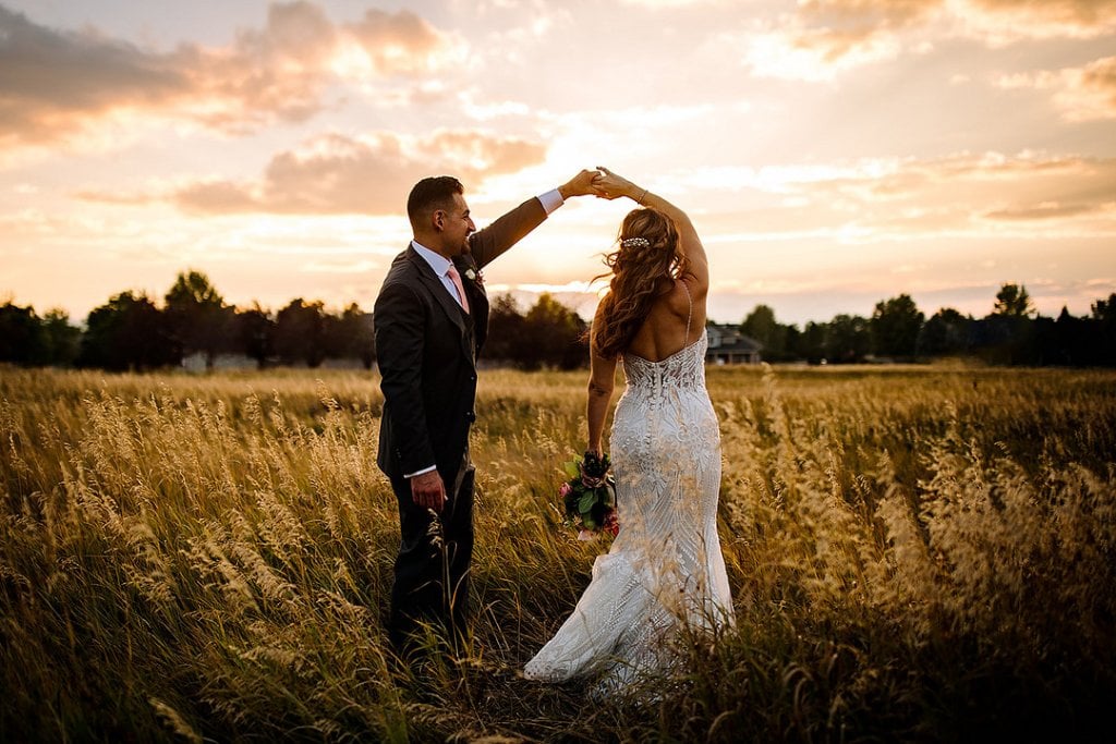 A man and woman dancing in a field at sunset, wedding celebration, romantic outdoor wedding.