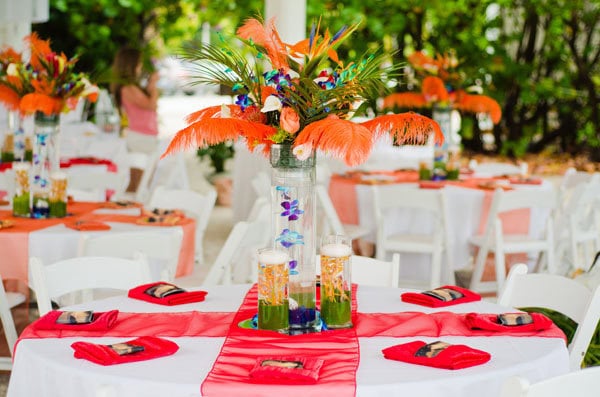 A colorful tropical-themed wedding reception table with vibrant floral centerpiece.
