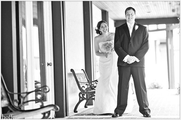 A smiling bride and groom standing indoors before their wedding ceremony.