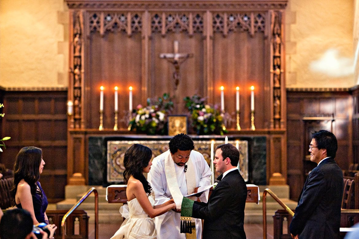 Wedding ceremony in church with bride, groom, and officiant at altar.