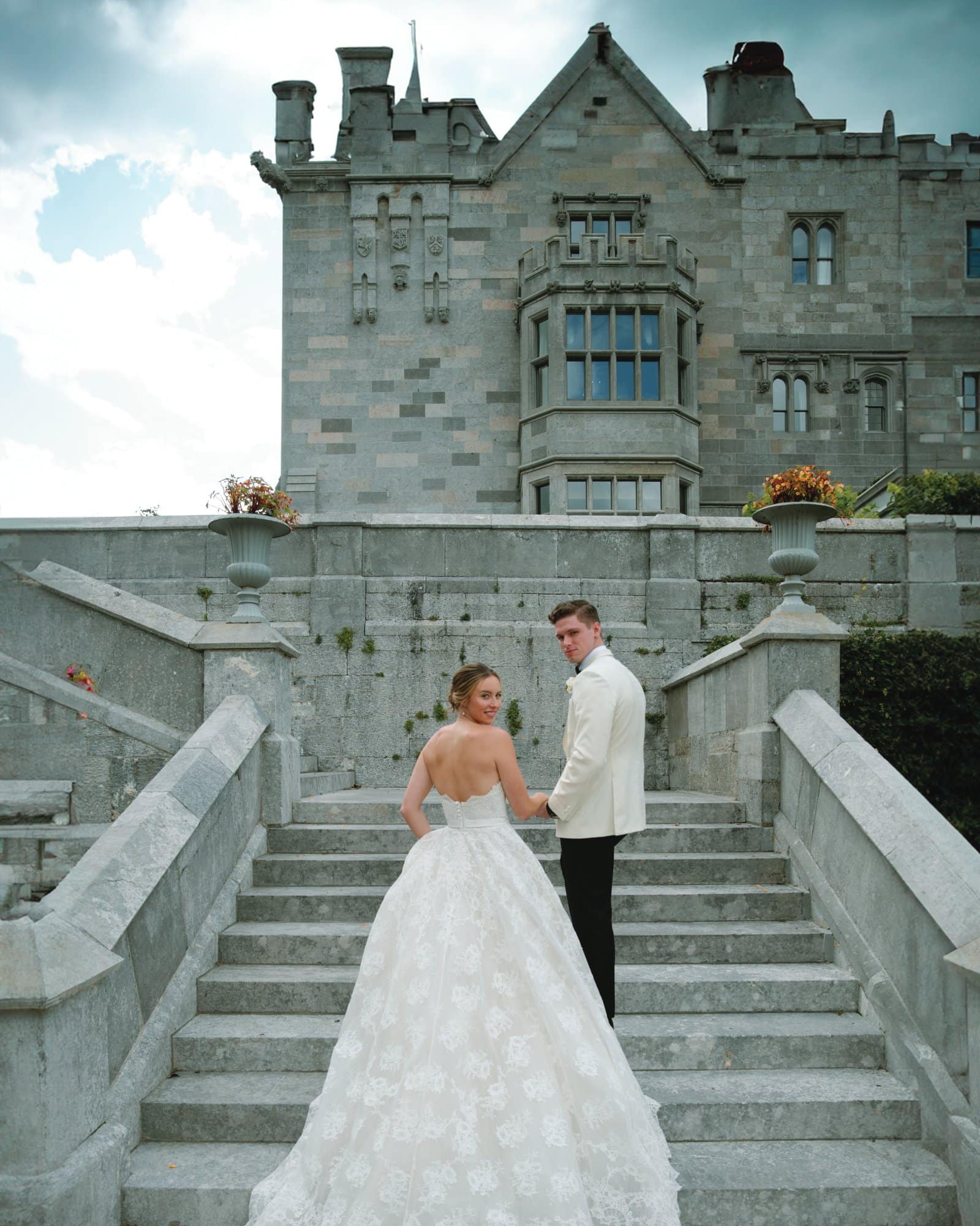 Bride and groom holding hands on castle staircase before wedding ceremony.