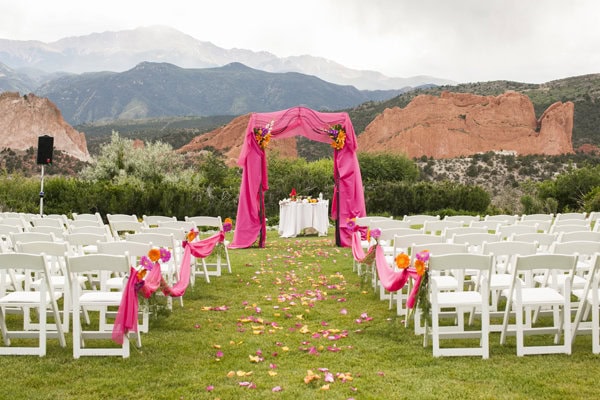 Beautiful outdoor wedding setup with pink drapery and floral decorations in a scenic mountain valley.