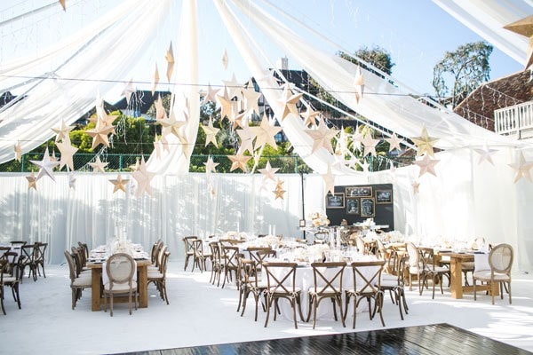 Elegant outdoor wedding reception with star-shaped decorations and white drapery.