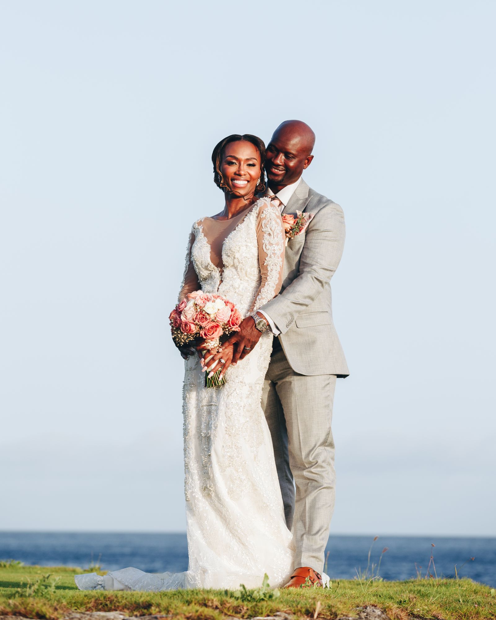 Happy bride and groom embracing outdoors on their wedding day by the sea.