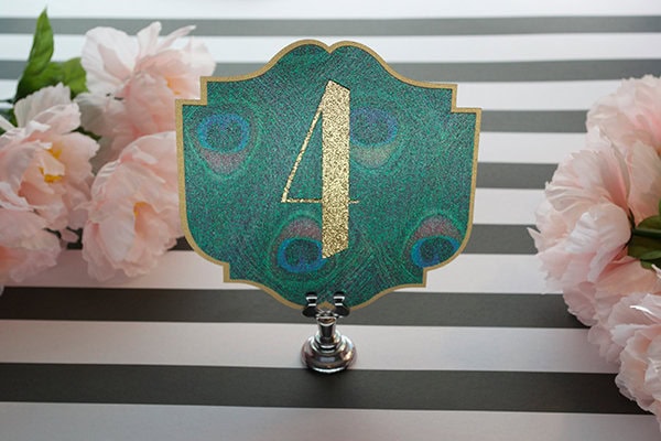 Elegant wedding table number 4 with peacock feather design and pink flowers decor.