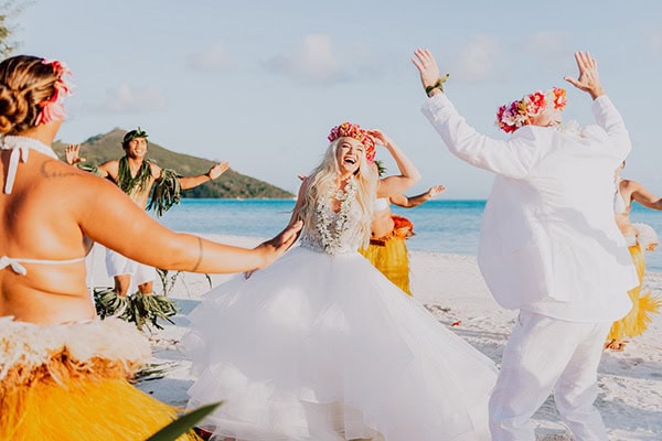 Hawaiian wedding celebration on the beach with dancing and floral leis.