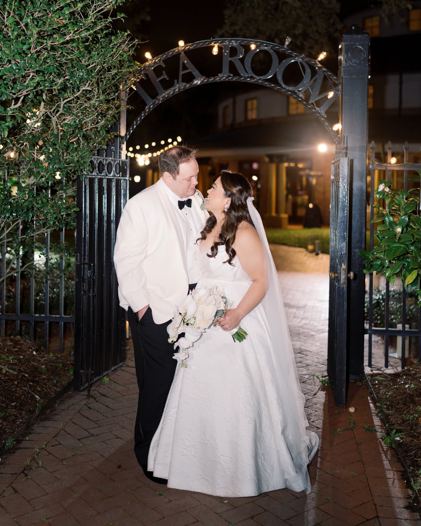 Bride and groom sharing a romantic moment at the entrance of a wedding venue at night.