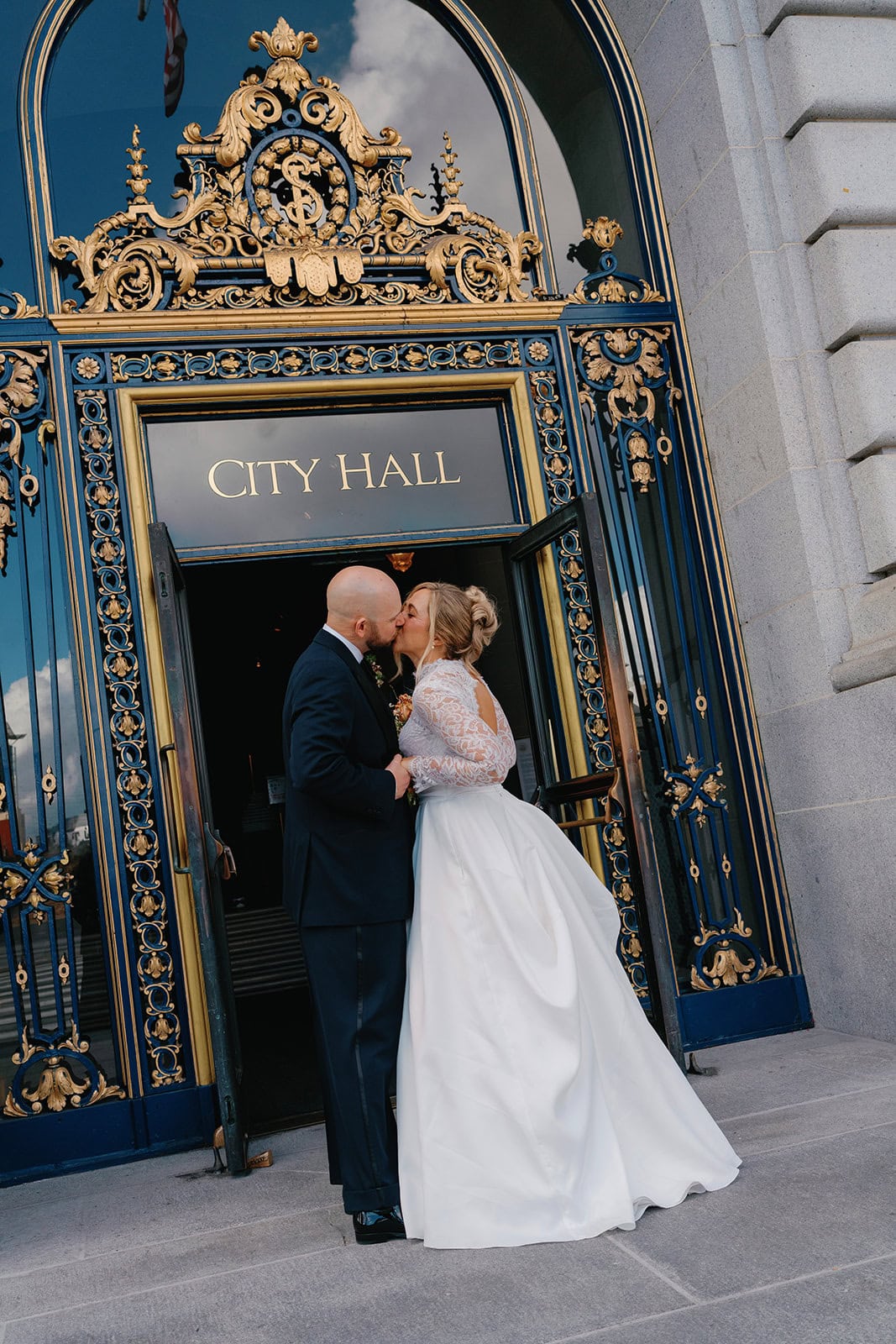 Bride and groom kissing outside city hall on wedding day.