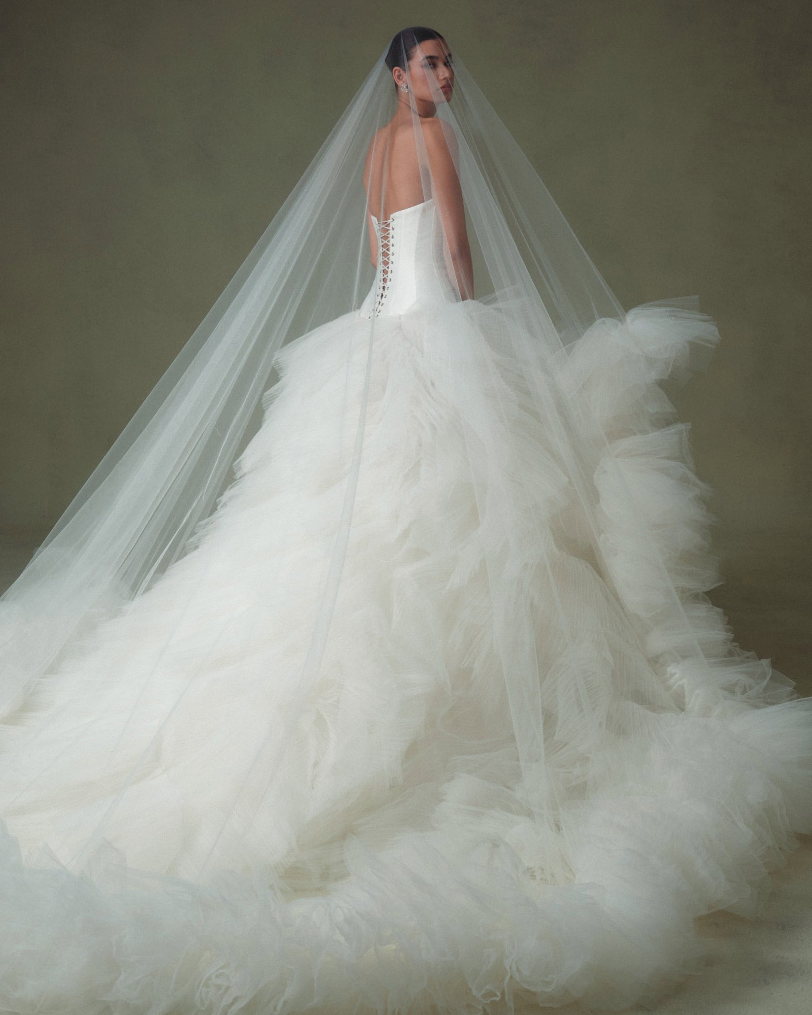 Elegant bride in a white wedding gown with a long veil and full skirt.