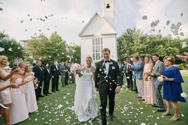 Bride and groom walking down aisle after wedding ceremony outside church with guests celebrating.