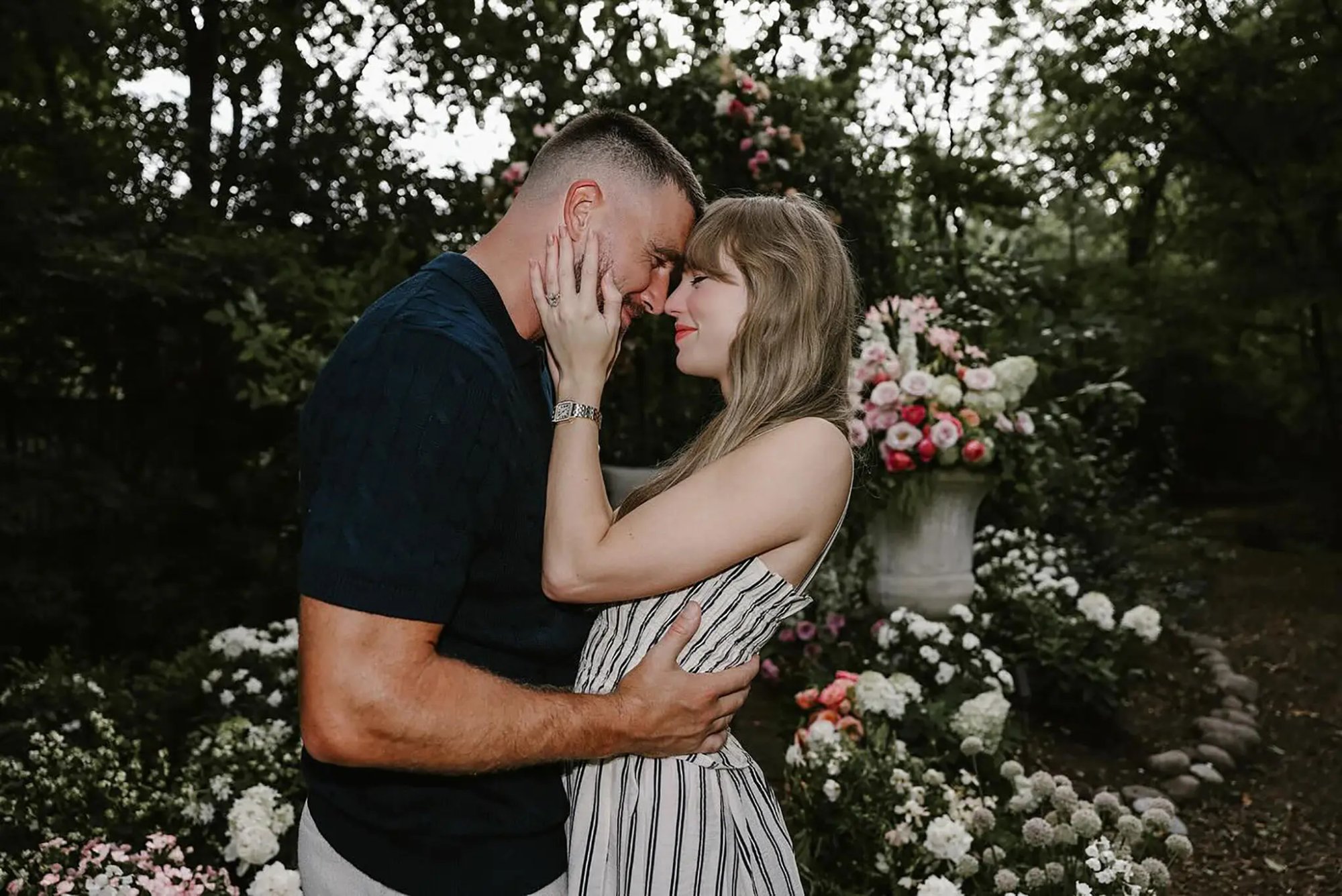 Couple sharing a romantic moment in a garden with floral arrangements.