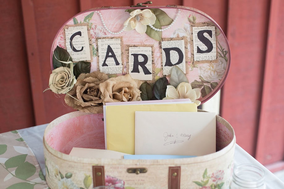 Vintage-style wedding card box with floral decorations and envelopes inside.