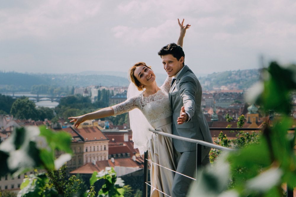 Happy newlyweds celebrating on a rooftop with city view in the background.